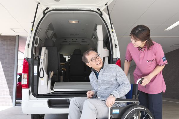 笑顔の高齢者とスタッフが交通手段を準備している様子