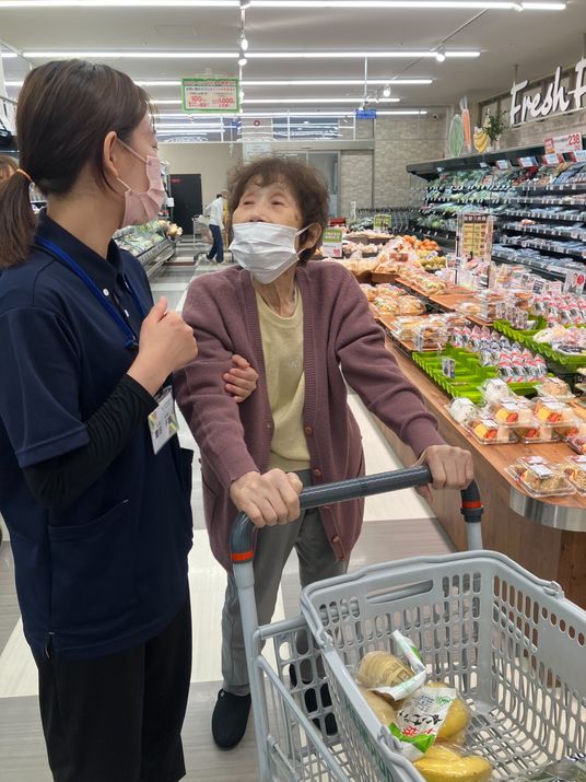 笑顔のスタッフと買い物中の利用者
