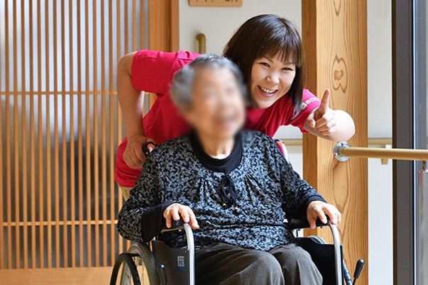 笑顔のスタッフと車椅子の女性の廊下  