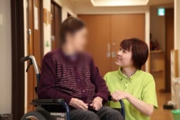 人と話す車椅子の女性 廊下