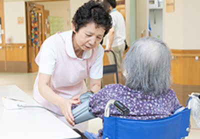 血圧測定する介護士と入居者