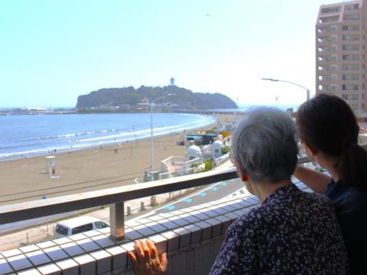 海を眺める入居者とスタッフ