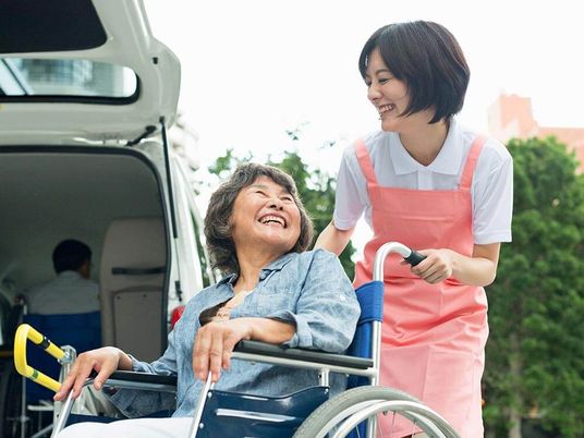 笑顔交わす車イスの女性とスタッフ