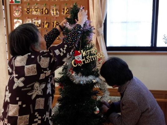 クリスマスツリー飾る人々